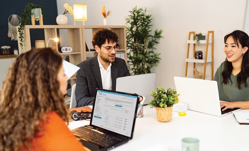 coworkers sitting at a table looking at their laptops